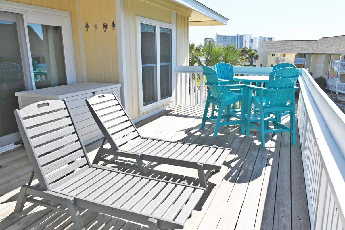 An exterior shot featuring deck chairs and an outdoor dining set on a deck surrounded by palm trees. The scene is tranquil and inviting, ideal for sunbathing, sharing meals, or enjoying a coffee or toast against a backdrop of sunset views.