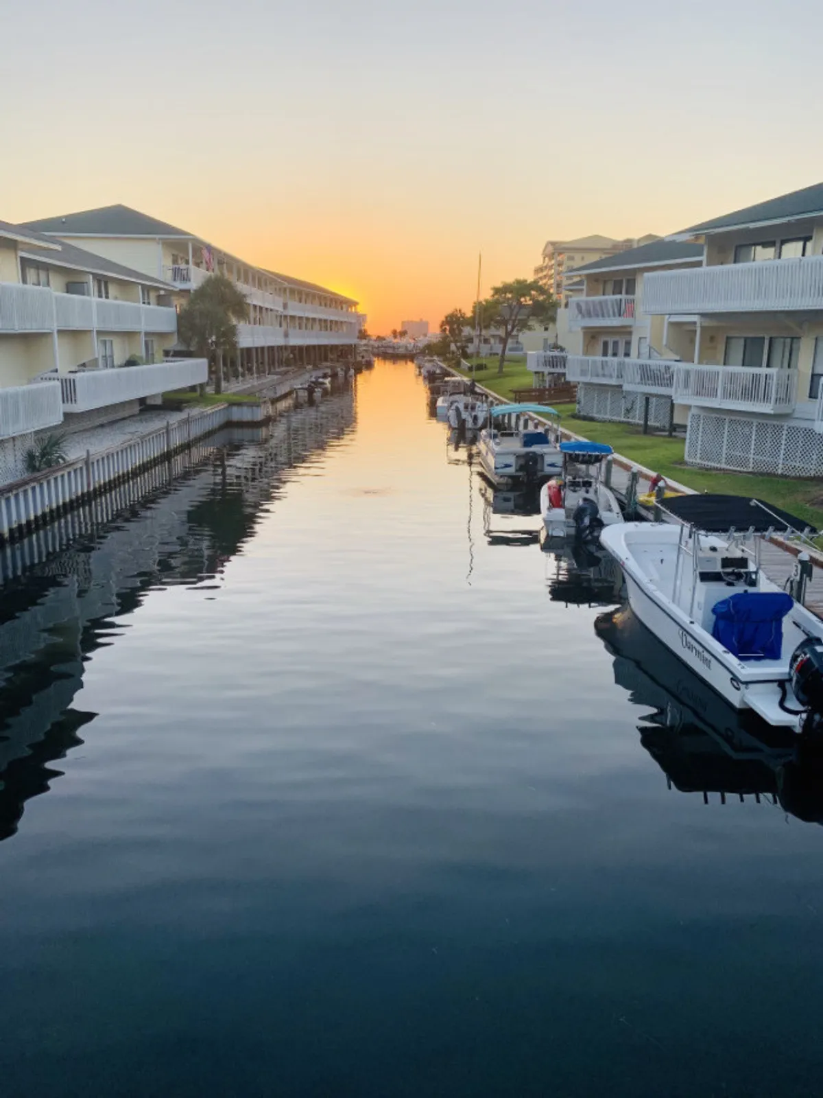 This image captures the still water of the canal at sunset, with vibrant sky colors reflected off the surface and boats docked along the canal. The tranquil setting is inviting and ideal for romantic moments, perfectly evoking a sense of serenity and waterfront charm.
