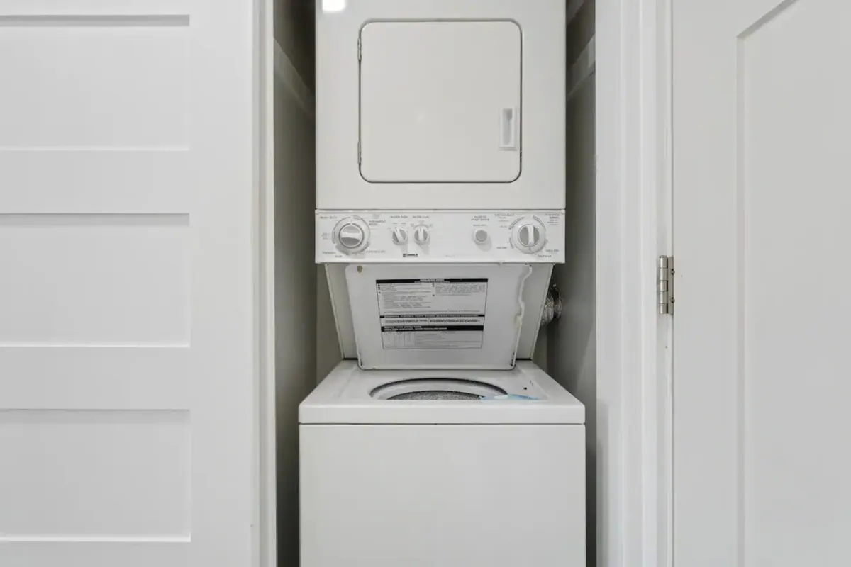 A practical laundry area featuring a stacked washer and dryer unit tucked neatly behind white paneled doors. The setup is clean and unobtrusive, offering added convenience for longer stays.