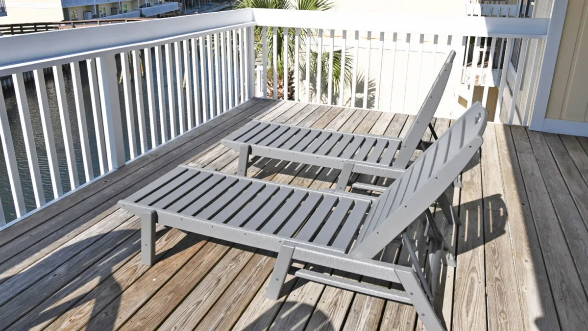 A tranquil back deck with two wooden lounge chairs overlooks a calm canal. The white railing frames the water, and the deck offers a peaceful setting for relaxing or socializing outdoors. The view is perfect for watching sunsets, fireworks, or airshows right from the comfort of home.